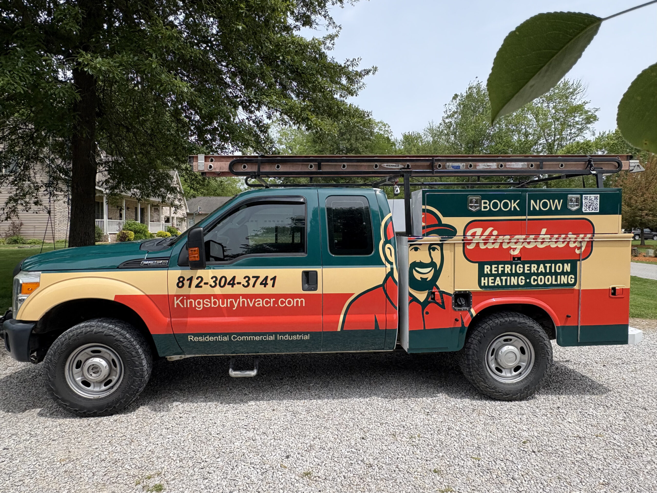 A Kingsbury HVAC service truck is parked on a gravel driveway, featuring company branding, contact info, and a mounted ladder on the roof.